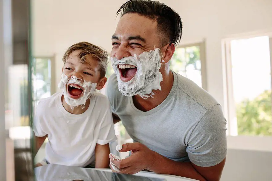 A father-son duo having fun as they foam their face with shaving cream