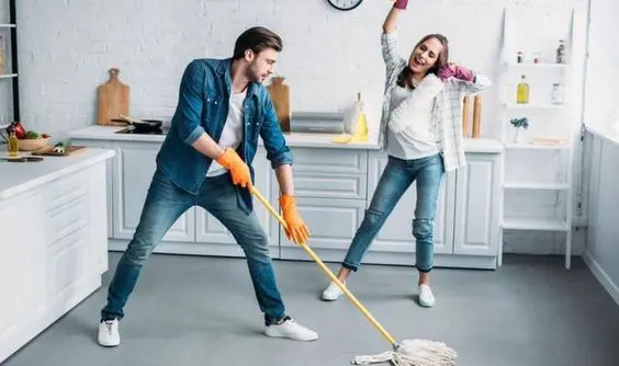 A couple enjoys cleaning their home together happily