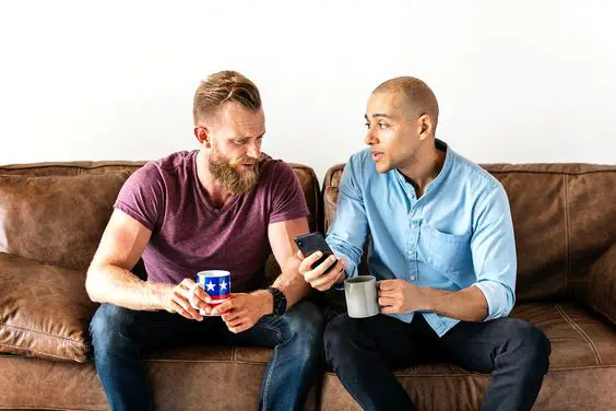 A man is seen showing something on his mobile phone to his friend